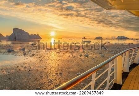 Cruise ship sails through wintry Cierva Cove - a deep inlet on the west side of the Antarctic Peninsula, ringed by Cierva Bay in San Martín Land - Antarctica, during a dramatic sunset 