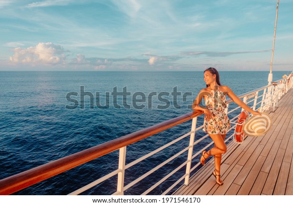 Cruise ship vacation travel luxury Caribbean\
holiday tourist woman watching sunset from balcony deck. Happy\
Asian woman enjoying\
holidays.