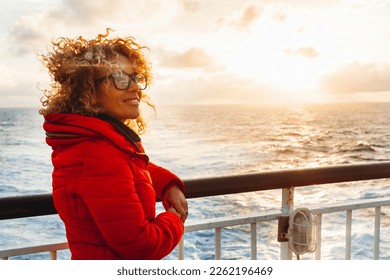Cruise ship vacation woman enjoying sunset on travel at sea. Traveler happy woman in red jacket looking at ocean relaxing on luxury cruise liner boat. People and ferry boat transport. Travel activity - Powered by Shutterstock