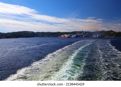 Cruise Ship Wake On North Sea With Kristiansand, Norway Visible In Background. Pollution Fumes Seen In Background.