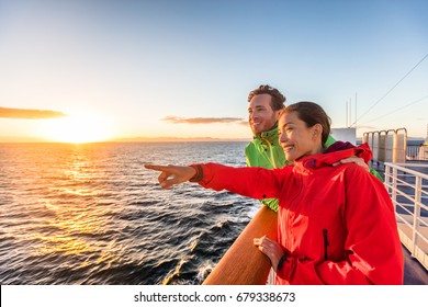 Cruise Travel Tourists Couple Pointing At Sea View From Ferry Tour. Asian Woman Multiracial People Traveling Together At Sunset.