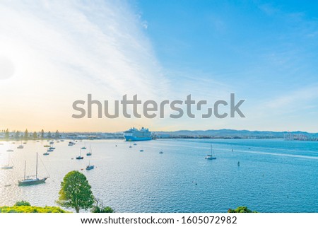 cruiseship leaving Tauranga Harbour at sunrise with bright light of sun illuminating from side.