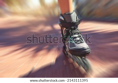 Cruising along. Closeup shot of a young womans feet in rollerblades speeding down a park path.
