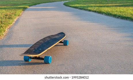 Cruising Longboard With Blue Wheels On A Paved Bike Trail In Summer Scenery In Northern Colorado - Boyd Lake State Park