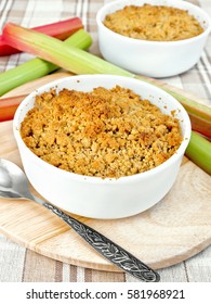 Crumble with rhubarb in two white bowls, stems against a linen tablecloth