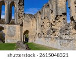 The crumbling ruins of a stone abbey stand against a vibrant blue sky at Byland Abbey - North York Moors - Byland - North Yorkshire - Great Britain
