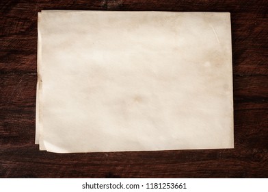 Crumpled aged paper with spot and stain on Dark wooden table