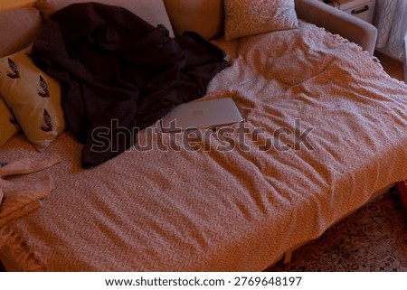 Crumpled bedspread with tablet and jacket, soft warm light, patterned cushion, nearby rug, remote workers latenight break, subtle clutter, relaxed atmosphere, functional home