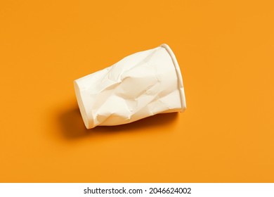 Crumpled blank paper cup on color background