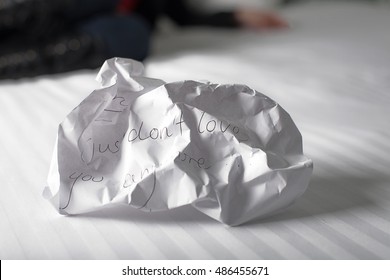 Crumpled Up Break Up Letter Sitting Discarded On A Bed With Woman In Background