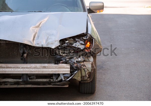 Crumpled car stands on road with\
Broken hood after car accident with nobody. Wrecked car that cannot\
be restored and repaired for Car dump On road with copy\
space.