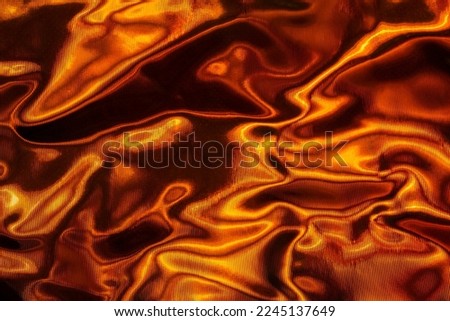 Crumpled foil with light playing on its surface. Visual effect. Abstract orange-black background