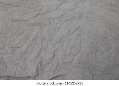 Crumpled linen fabric texture of coarse gray fabric, burlap background in close up, weave threads, fabric after washing, un-ironed canvas