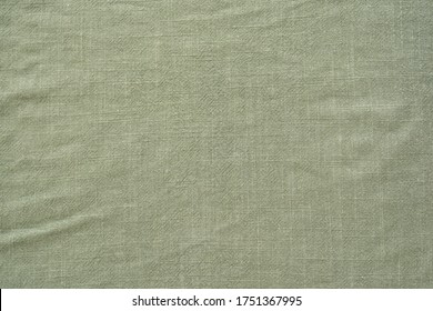 Crumpled linen textile fabric of khaki color as background, top view