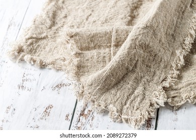 Crumpled natural linen kitchen serviette towel on vintage wooden table. Rustic background with copy space