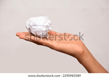 Crumpled paper ball in hand on white background.