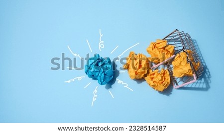 Crumpled paper balls on a blue background and a shopping basket. Concept of a new idea