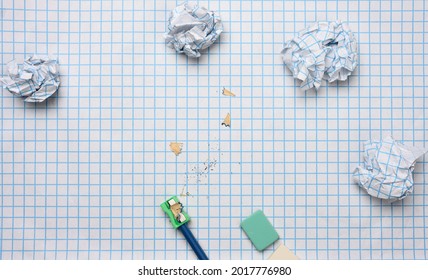 crumpled paper balls and a sharpened wooden pencil with shavings on a checkered paper sheet - Powered by Shutterstock