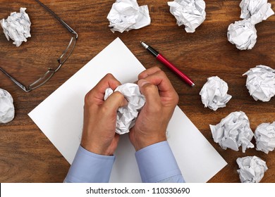 Crumpled paper and businessman tearing up another paper ball for the pile