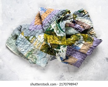 crumpled patchwork scarf sewn from various crinkled silk fabrics on gray conctete backhround