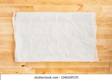 Crumpled piece of white parchment or baking paper on wooden table. Top view. Copy space for text and design element.