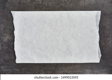 Crumpled piece of white parchment or baking paper on black concrete background. Top view. Copy space for text and design element.