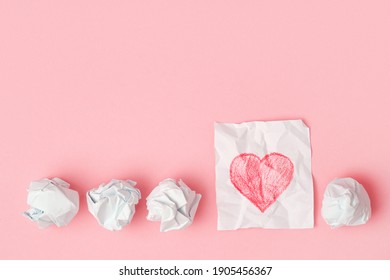 Crumpled pieces white paper   one unfolded  Red pencil drawn heart  Progress love 