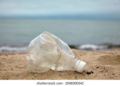 Crumpled plastic bottle on the sandy beach against the background of the sea Day Recycling