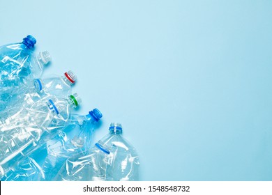 Crumpled plastic bottles on a blue background. Plastic trash. Copy space for text