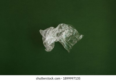Crumpled plastic polyethylene bag on a green background. Contamination of the planet. Clear plastic bag. Zero waste concept.