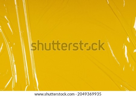 Crumpled plastic transparent plastic cellophane on yellow color background. Abstract creative texture background