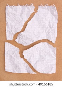 Crumpled ragged note paper isolated on brown board