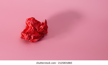 Crumpled Red Paper On A Pink Background With A Trend Shadow. Screwed Up Craft Paper Ball. Junk Paper Can Be Recycle
