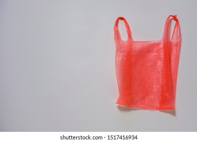 Crumpled Red Plastic Single Use Carrier Bag Or Shopping Bag On Grey With Copy Space In A Conceptual Image