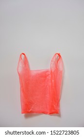 Crumpled Red Plastic Single Use Carrier Bag Or Shopping Bag On Grey With Copy Space In A Conceptual Image