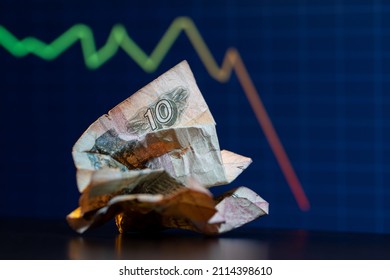 Una nota de diez rublos rusos se derrumbó frente a una tabla de operaciones descendente.
10 rublos de Rusia. La caída del rublo. Colapso del rublo.