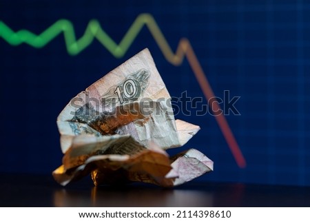 Crumpled Russian ten ruble note in front of falling down trading chart.
10 ruble bill of Russia. The fall of the ruble. Collapse of the ruble.