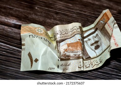 Crumpled Saudi Arabia money of 10 SAR ten riyals isolated on wooden background, wrinkled 10 Saudi Riyals cash bill banknote, Saudi money inflation and economy world crisis concept, selective focus