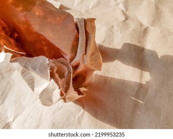 A Crumpled Sheet Of Craft Paper In A Ball On The Background, Top View, Bright Sunlight And Shadow.