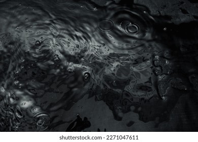 Crumpled textured dark fabric lies in the water. Abstract image with beautiful highlights for your creative design or stylish illustrations.