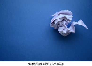 Crumpled wad of white paper on a blue background. - Shutterstock ID 2129086283
