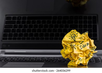 Crumpled Yellow Paper Ball With Idea On The Laptop.