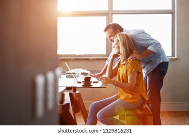 Crunching The Home Finance Numbers. Shot Of A Mature Couple Sitting At Their Dining Room Table Doing Online Banking Using A Laptop.