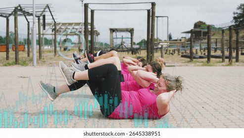 Crunching six women in pink tops lying with knees bent on paved courtyard, with pull-up bars. Group fitness, outdoor workout, high energy, team training, athletic, strength training, community