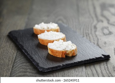 Crunchy Baguette Slices With Cream Cheese On Slate Board