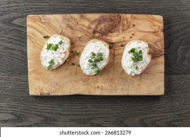 crunchy baguette slices with cream cheese and green onion on olive board - Powered by Shutterstock