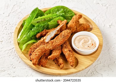 Crunchy Baked Chicken Tenders On A Plate With Fresh Romaine Leaves And Dipping Sauce, Horizontal View, American Cuisine