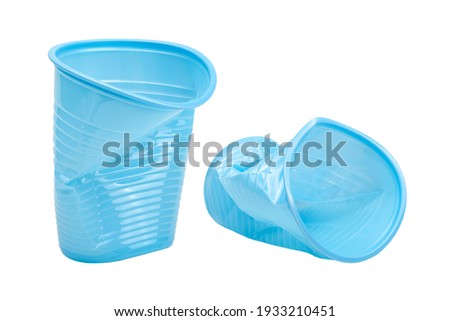 Crushed, damaged, discarded blue empty plastic cups, objects isolated on white background, cut out. Used plastic beverage cup trash, throwing away used plastic water cups, garbage, rubbish concept