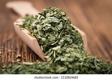 Crushed Dried Basil Leaves In A Wooden Scoop