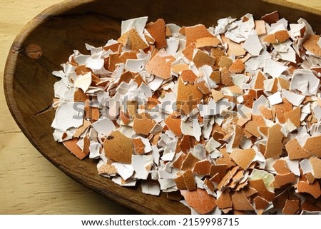 CRUSHED EGGSHELLS IN A WOODEN BOWL